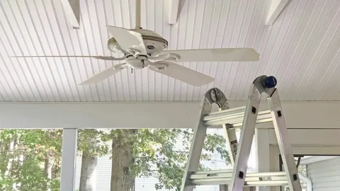 Ceiling fan being installed to reduce humidity and prevent lameness risks in barns.