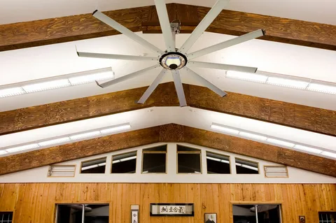 HVLS ceiling fan cooling a wooden roof sport hall as smarter alternative to air conditioning.